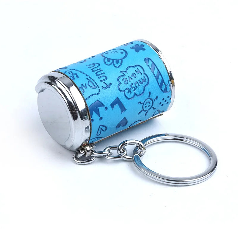 A light blue cylindrical coin holder keychain featuring a pattern of cute, hand-drawn text and icons.
