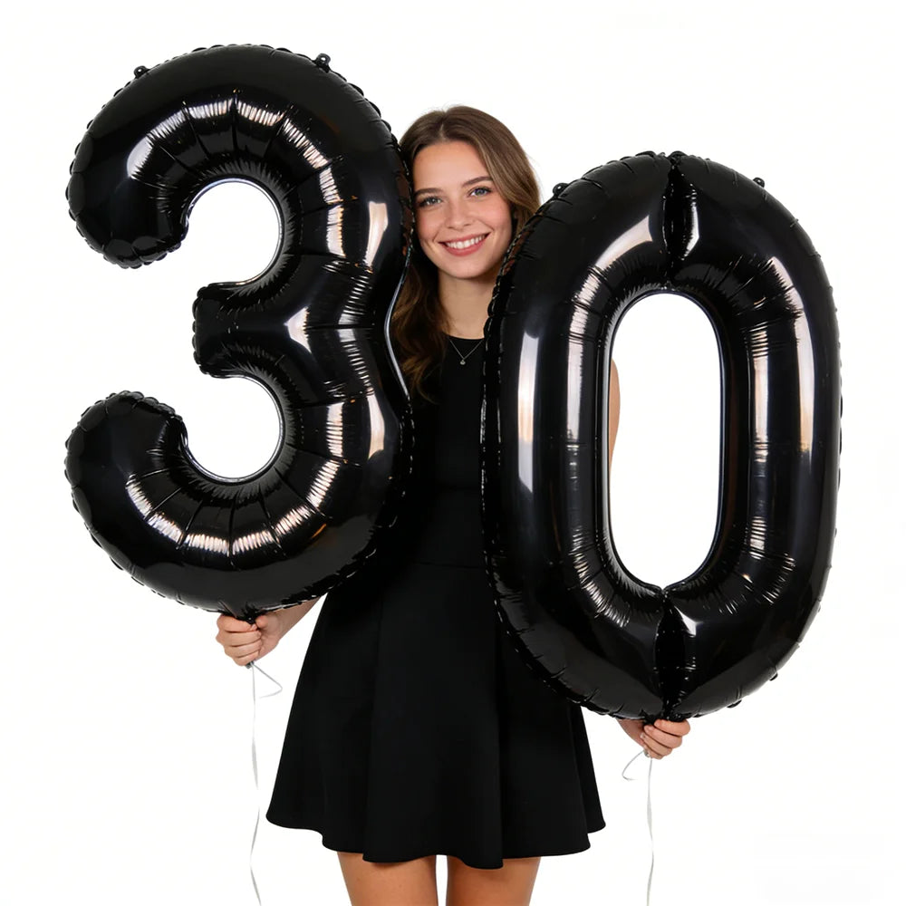 Two black foil balloons shaped like the number 30 held by a smiling woman.