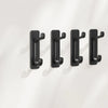 A set of four black self-adhesive wall hooks mounted on a white surface.