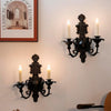 A vintage black wall pendant candle holder mounted on a white wall.