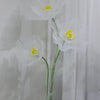 A large artificial silk white poppy flower with a yellow center displayed on a green stand.