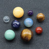 A collection of nine natural crystal gemstone spheres in various colors including yellow, purple, blue, green, and orange ton