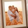 A framed photo of a man and a girl standing in a golden field at sunset.