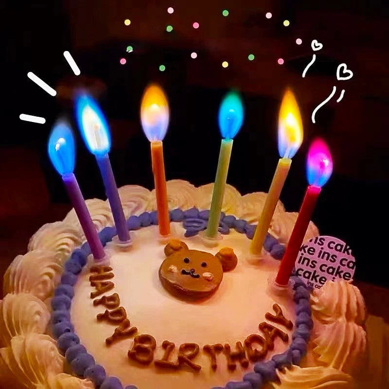 Birthday cake decorated with colorful flame candles and icing, set against a dark background.