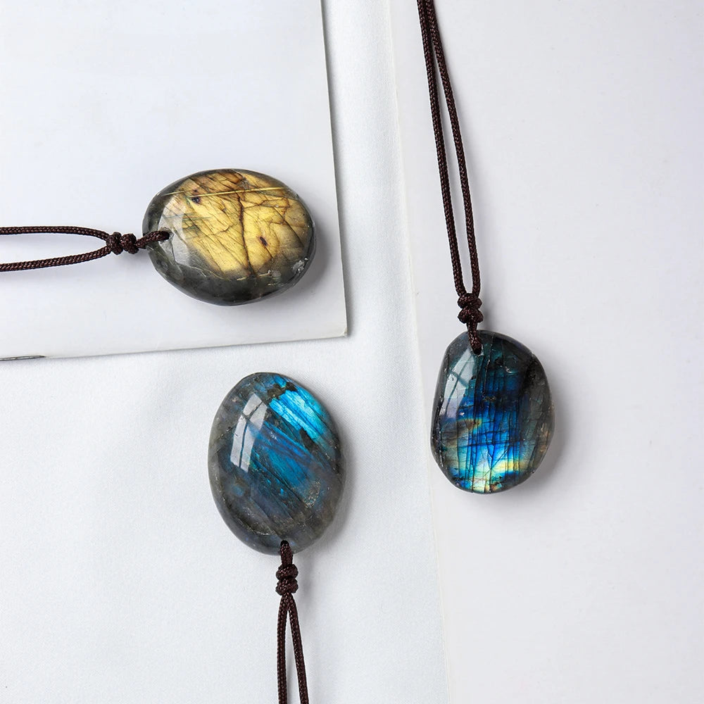 A necklace featuring two labradorite pendants, one golden-yellow and one blue-green, suspended by dark cord.