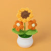Handmade knitted orange sunflower with a yellow center growing in a white pot.