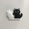 A black glitter cat figurine and a white acrylic bottle are displayed on a white magnetic strip.