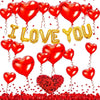 A set of red heart balloons decorated with roses and bears lying on a bed of red petals.
