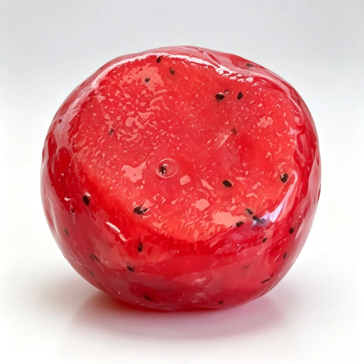 A bright red, translucent watermelon-shaped squishy fidget toy with small black dots.