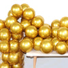 A cluster of metallic gold balloons piled on a white table for party decorations.