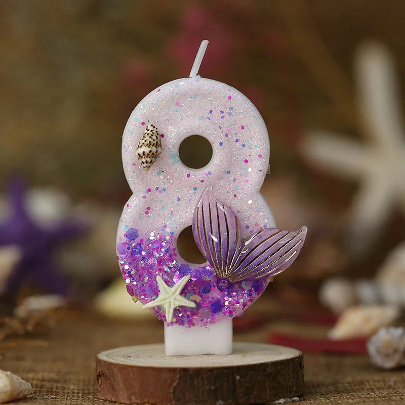 A white birthday candle shaped like the number eight decorated with purple glitter and a silver starfish flower.