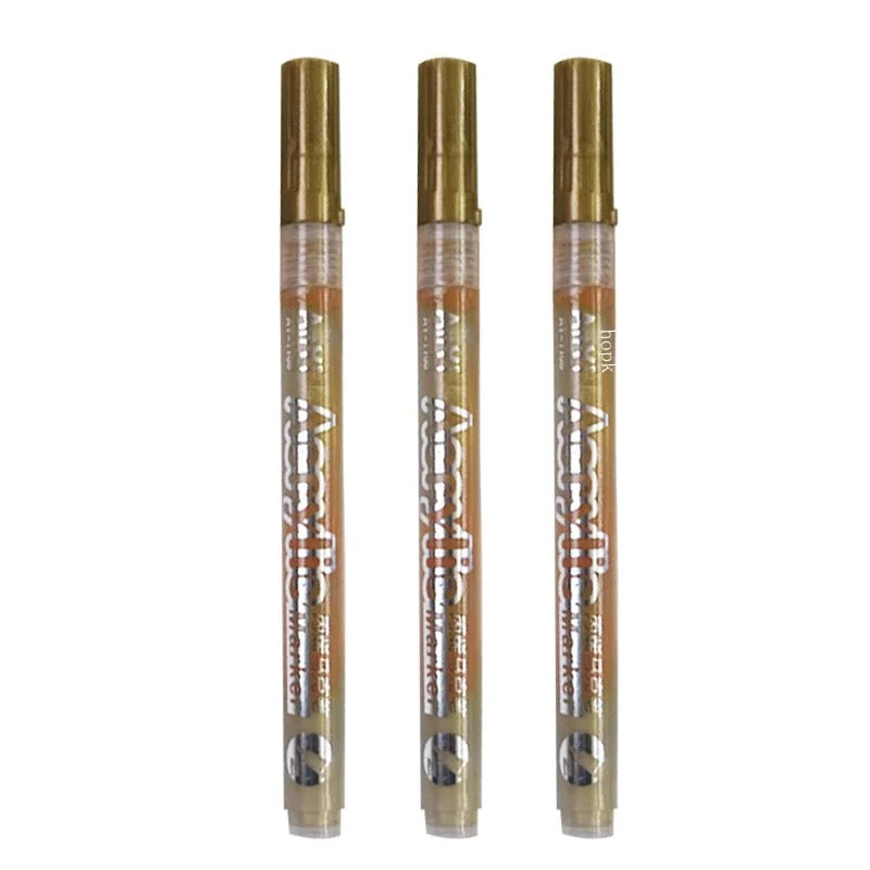 A set of six extra-fine point acrylic paint pens in gold and clear packaging.