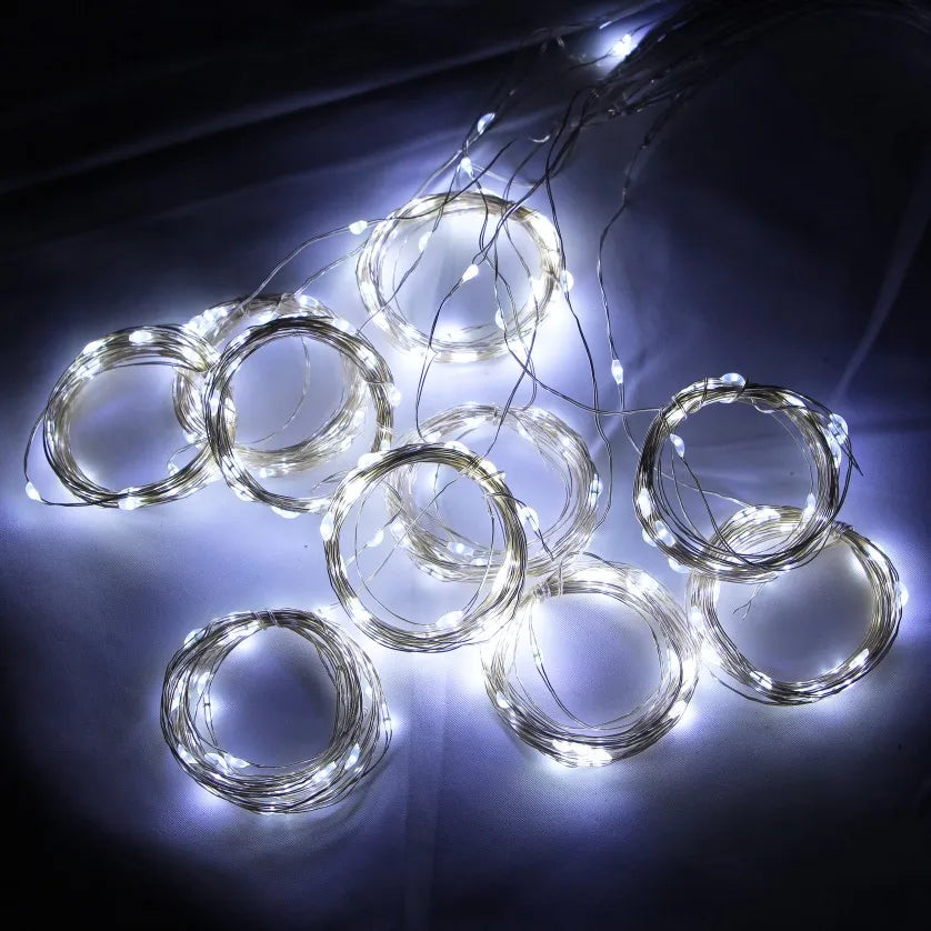 A cluster of glowing white LED curtain fairy lights arranged in various circular shapes against a dark background.