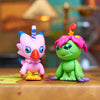 A pink and green Digimon Adventure collectible figure set featuring a bird-like monster and a dinosaur-like monster.