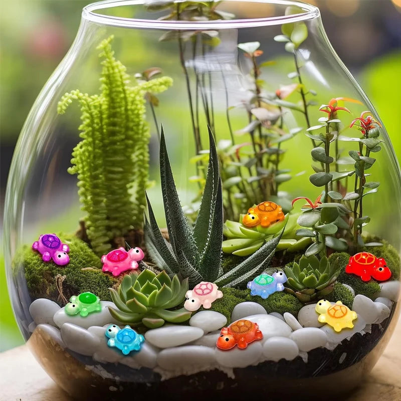 A glass terrarium filled with various glow-in-the-dark resin turtle figurines and green succulent plants.
