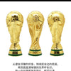Gold trophy figurine with a green base, representing the FIFA World Cup 2026.