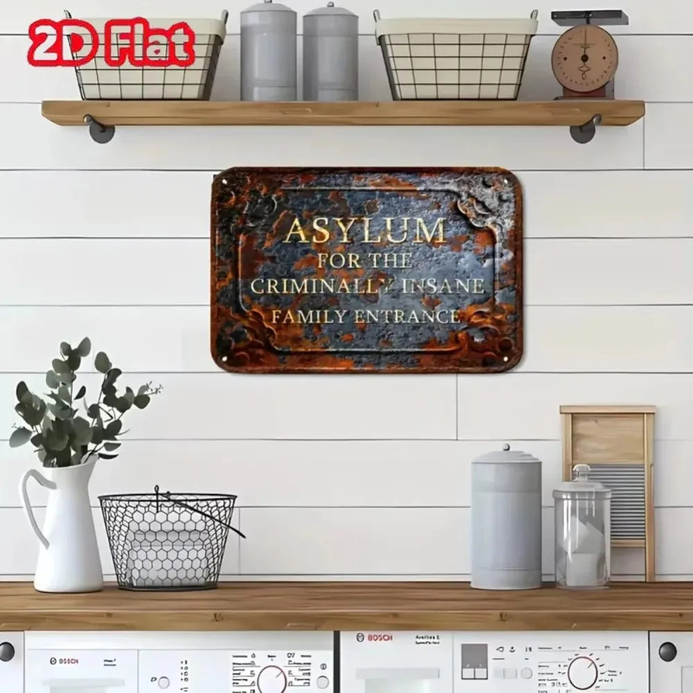 A vintage metal sign with the text Asylum for the Criminally Insane Family Entrance mounted on a wooden shelf.