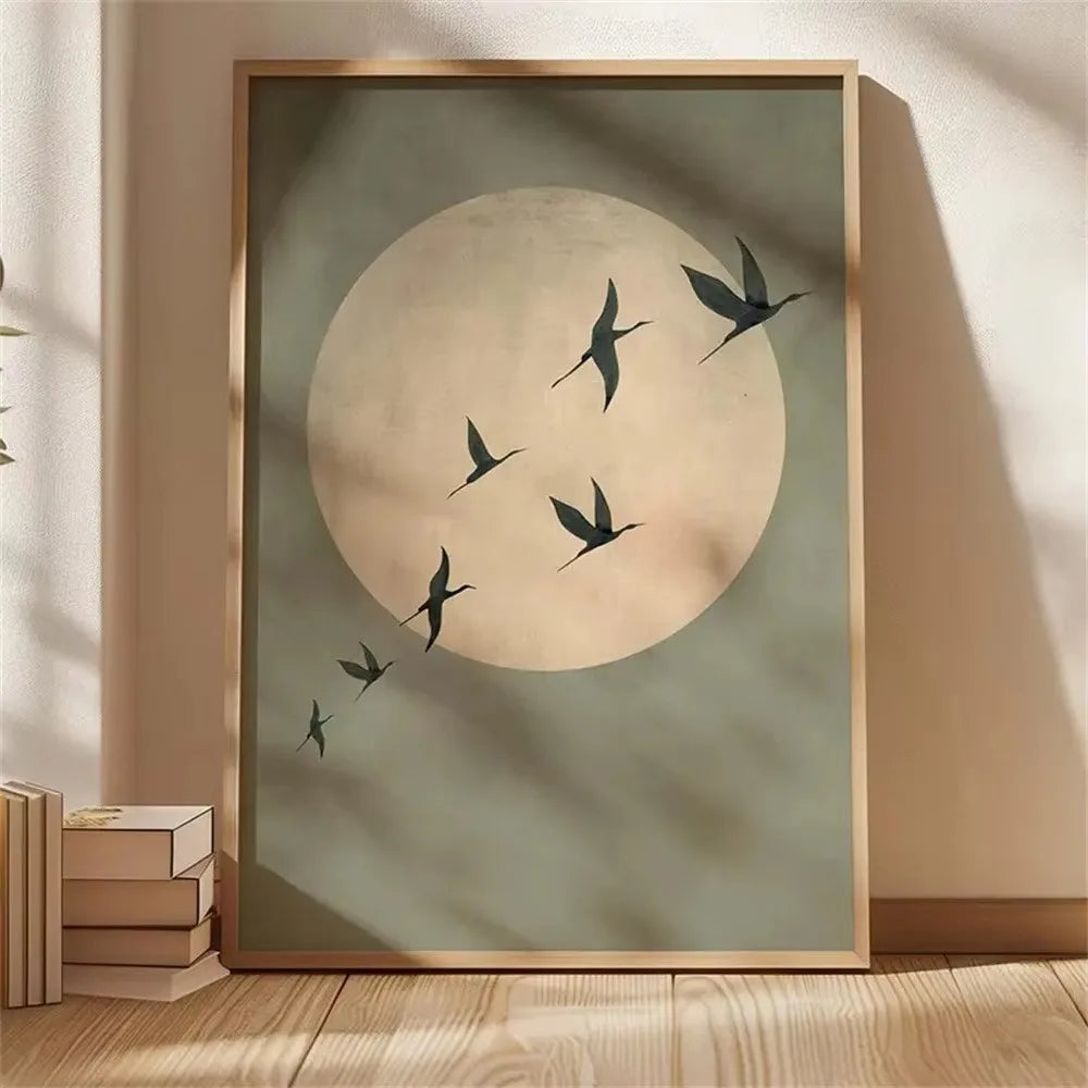 A framed canvas wall art featuring a large pale circle resembling a moon with several dark silhouettes of cranes flying acros