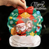 A hand is holding a green reusable Christmas gift bag decorated with Santa, bells, and festive elements.