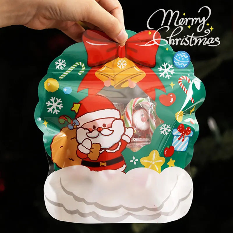 A hand is holding a green reusable Christmas gift bag decorated with Santa, bells, and festive elements.