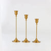 A set of three ornate vintage metal candle holders with brass finish.