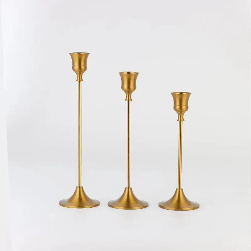 A set of three ornate vintage metal candle holders with brass finish.