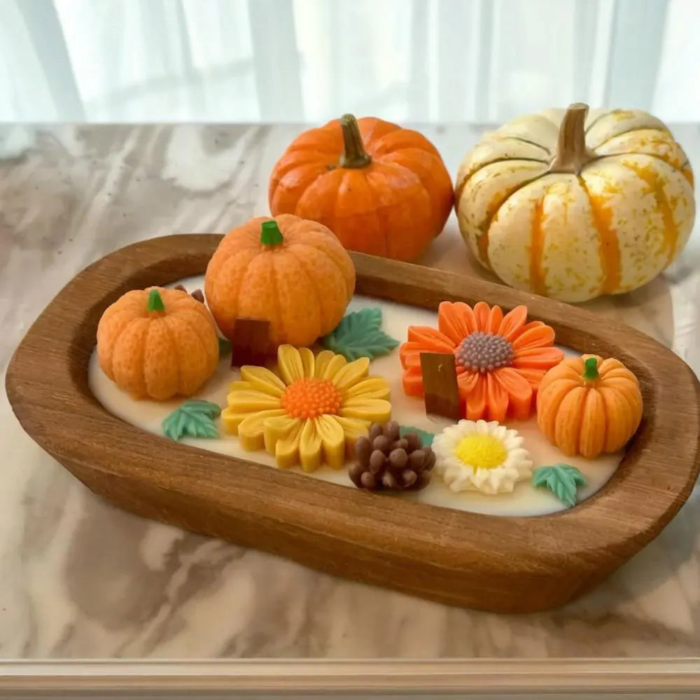 A wooden tray holds several carved pumpkins and flowers, likely used for a fall scented candle making kit.