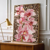 Pink leopard hibiscus canvas wall art framed in gold on a wooden cabinet.