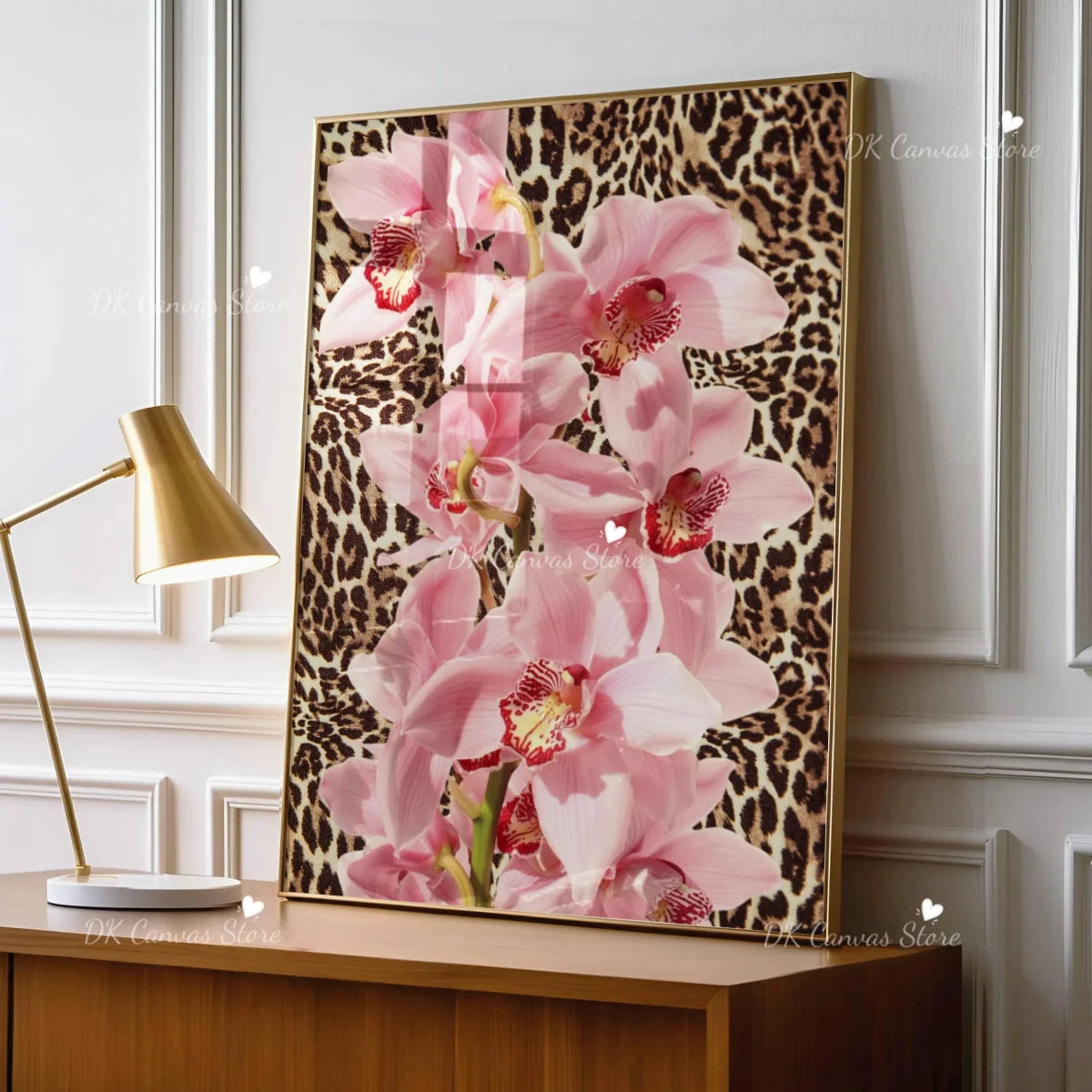 Pink leopard hibiscus canvas wall art framed in gold on a wooden cabinet.