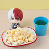 A collectible figure of Izuku Midoriya from My Hero Academia displayed next to a cup of green tea and popcorn.