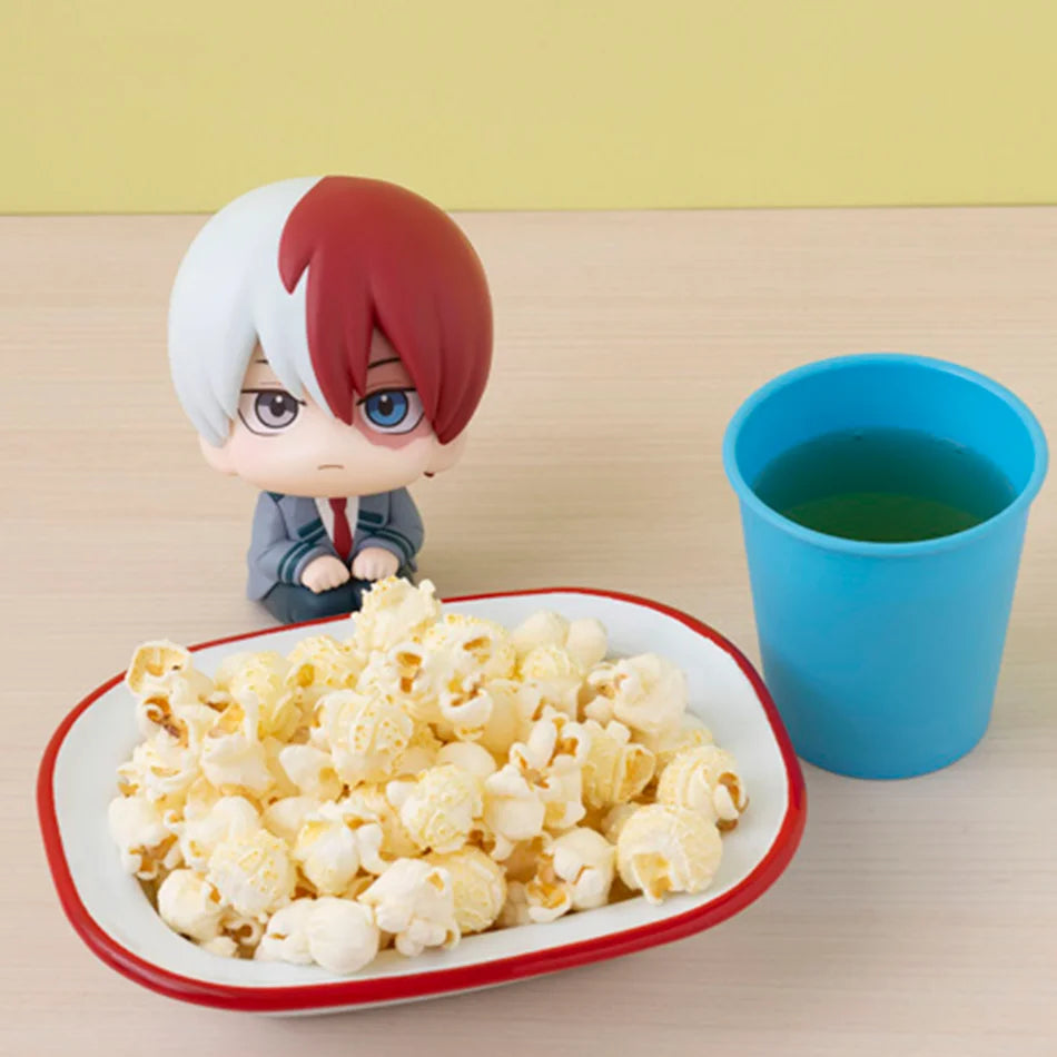 A collectible figure of Izuku Midoriya from My Hero Academia displayed next to a cup of green tea and popcorn.
