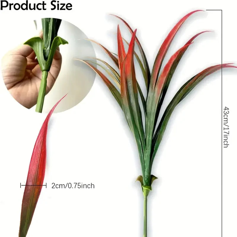 A vibrant, tall artificial grass plant with red and green leaves shown next to a hand for scale.