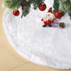 White plush Christmas tree skirt with a snowflake design decorated with red ornaments and pinecones.