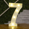 A glowing warm white LED alphabet letter light shaped like the number seven resting on a wooden surface.