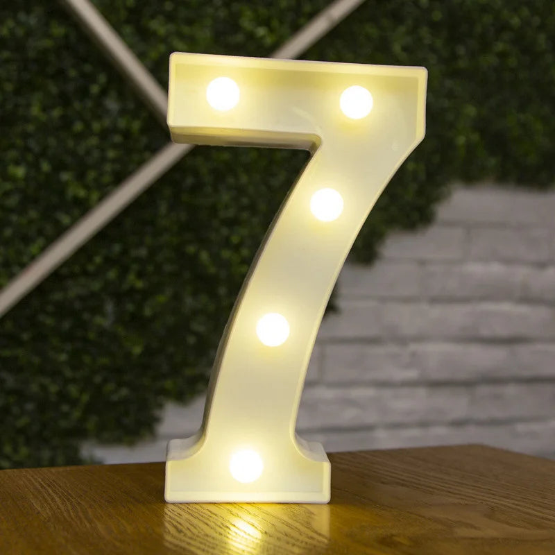 A glowing warm white LED alphabet letter light shaped like the number seven resting on a wooden surface.