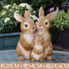 A pair of hand-painted resin rabbit garden statues sitting together on a dark surface.