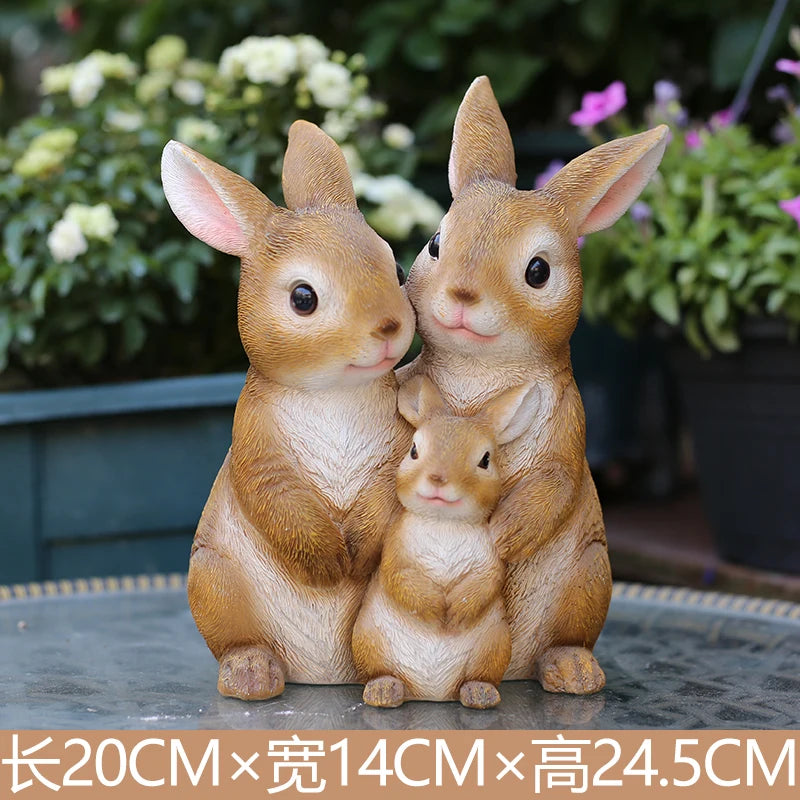 A pair of hand-painted resin rabbit garden statues sitting together on a dark surface.