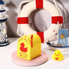 A yellow magnetic duck mailbox cover rests on a pink circular base next to a white life preserver.