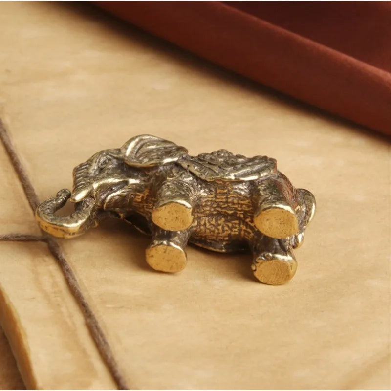 Antique bronze elephant figurine with a textured surface resting on light brown paper.