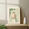 Vintage tiger cat wall art poster featuring a tabby cat looking at a newspaper against a pale green background.