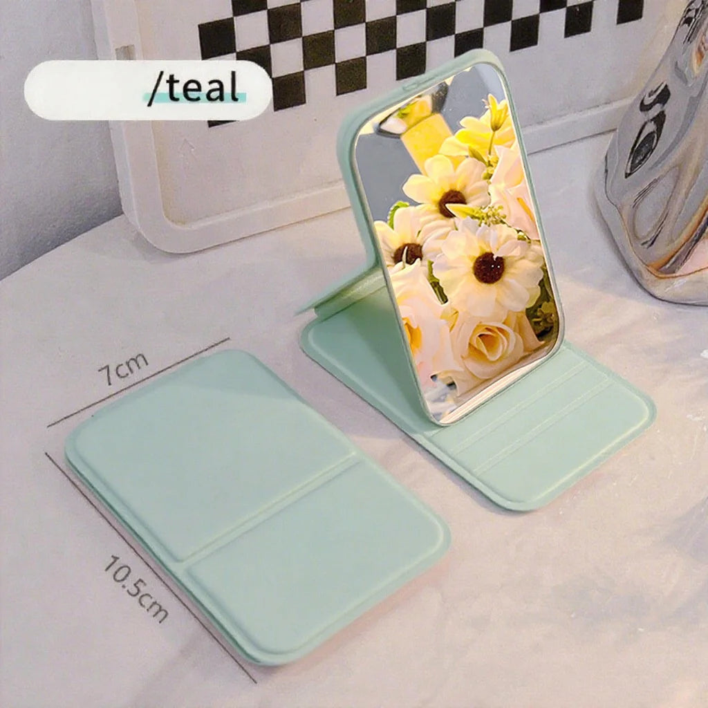 A light mint green portable folding HD makeup mirror with a floral design displayed on a white background.