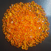 A pile of bright orange decorative crushed diamond acrylic pebbles.