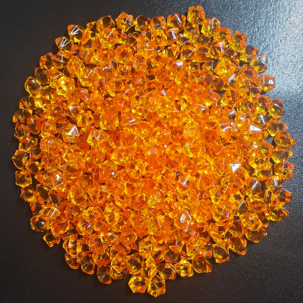 Une pile de galets acryliques décoratifs en diamant écrasé orange vif.