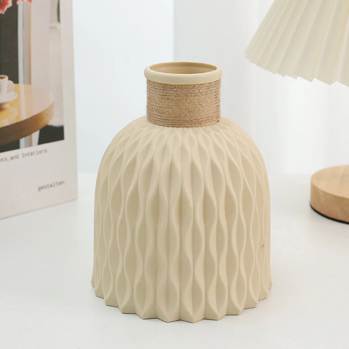 A beige ceramic vase with a textured surface and a woven straw rim, shown on a white surface.