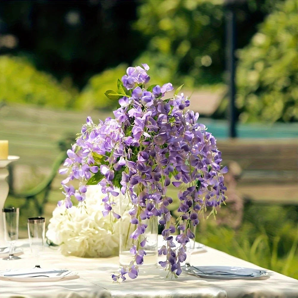 A cluster of purple artificial wisteria vine garland flowers displayed on a white tablecloth.