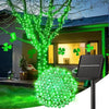 A string of bright green LED lights is displayed on a tree and ground, illuminating an outdoor garden area.