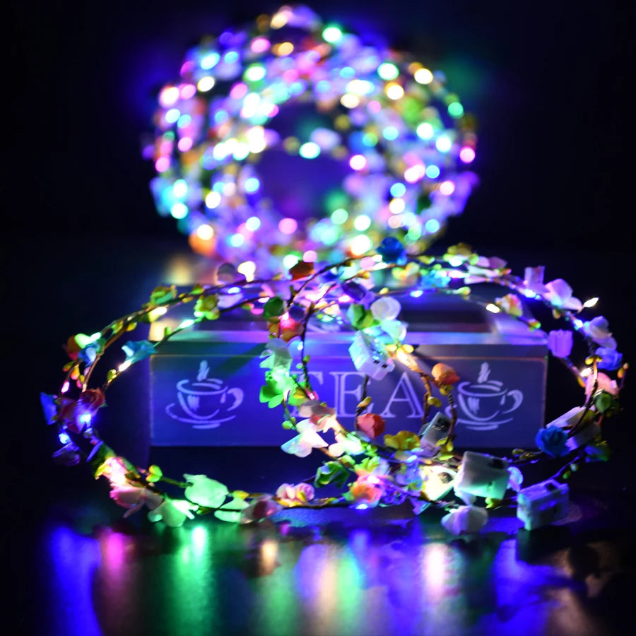 A glowing flower wreath headband with multiple colored LEDs resting on a reflective surface.