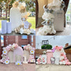 A white and gold floral arch backdrop for a first birthday party featuring balloons and decorative elements.