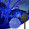 A solar-powered LED string light illuminates a large tree and a building at dusk for outdoor decoration.