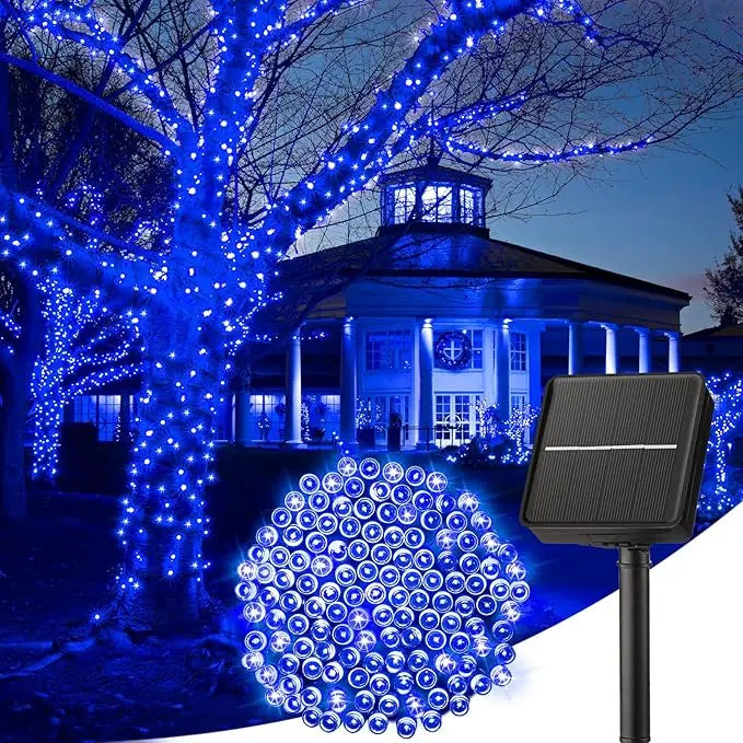 A solar-powered LED string light illuminates a large tree and a building at dusk for outdoor decoration.